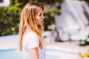Woman with long honey-blonde hair in a white t-shirt